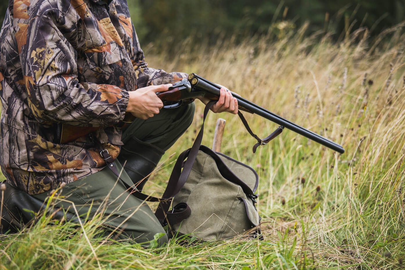 Jäger mit Flinte im hohen Gras bei der Jagd Jäger mit Flinte im hohen Gras bei der Jagd